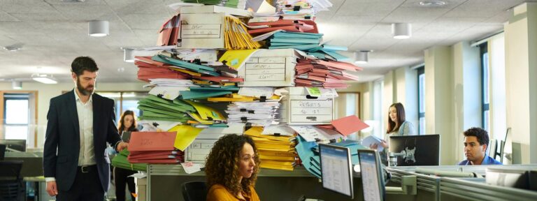 People in the office surrounded by pile of office documents